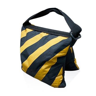 Black sandbag with bright yellow hazard stripes used to weigh down poster boards when placed outdoors