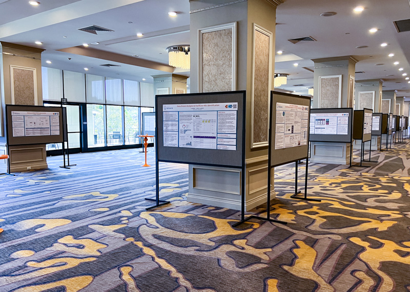 Printed research posters on pin boards in hallway around pillars